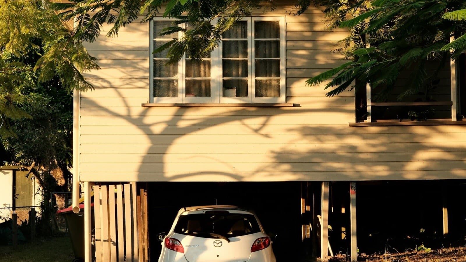 A car parked in the undercroft of a raised house