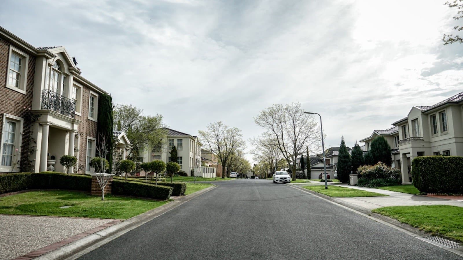 A wide residential road under an overcast sky